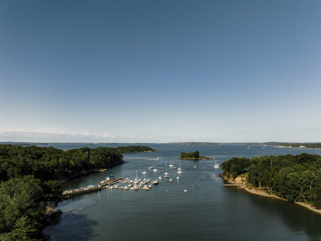 Aerial view of a coastal harbor with boats and tree-lined islands near Inn at Diamond Cove in Maine.