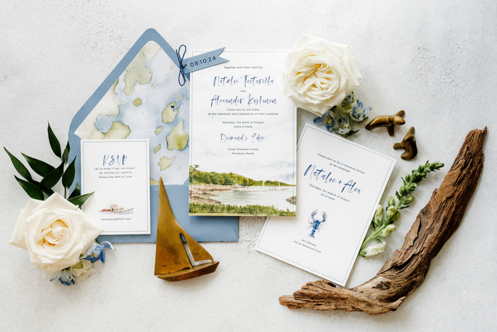 Coastal-inspired wedding invitation suite with map details, florals, and nautical elements arranged on a light background.