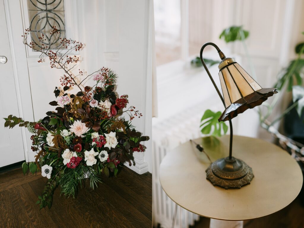 Left: Large, organic floral installation with mixed blooms and foliage near a doorway. Right: Vintage table lamp on a round side table beside a window.
