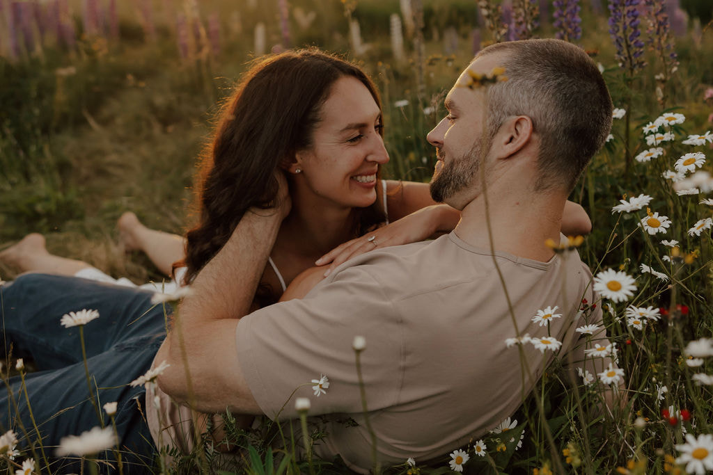 Couple lying together in a wildflower meadow during golden hour in the New Hampshire mountains.