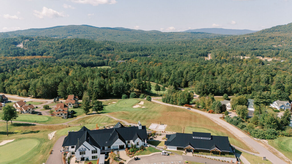 Aerial view of Owl’s Nest Resort surrounded by green mountains, golf course fairways, and forested landscape in New Hampshire.