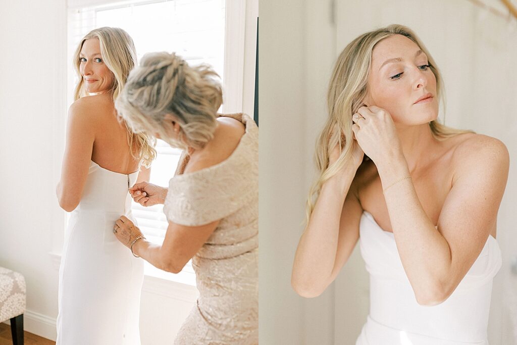 Bride getting her dress fastened and putting on earrings in soft window light during morning wedding preparations.