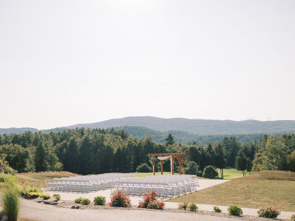 Outdoor wedding ceremony setup with white chairs and wooden arbor overlooking mountain views at Owl’s Nest Resort.