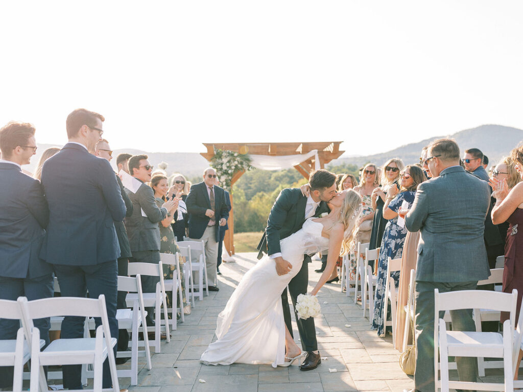 Bride and groom share a celebratory dip and kiss while walking back up the aisle after their ceremony.