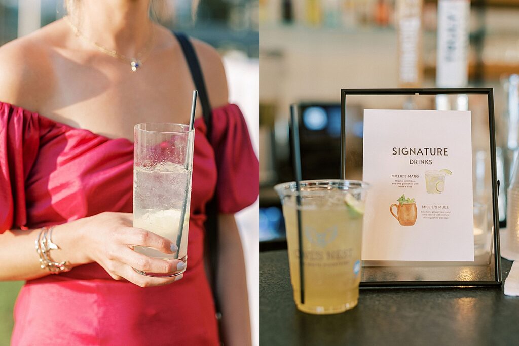 Guest holding a cocktail during outdoor cocktail hour and signature drink sign displayed at the bar.