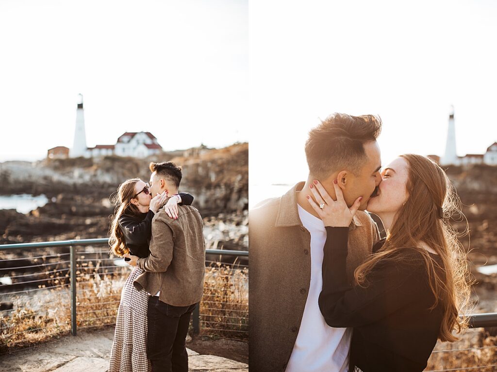 Couple embraces and kisses after proposal along rocky coastline with lighthouse in background during golden hour engagement session.