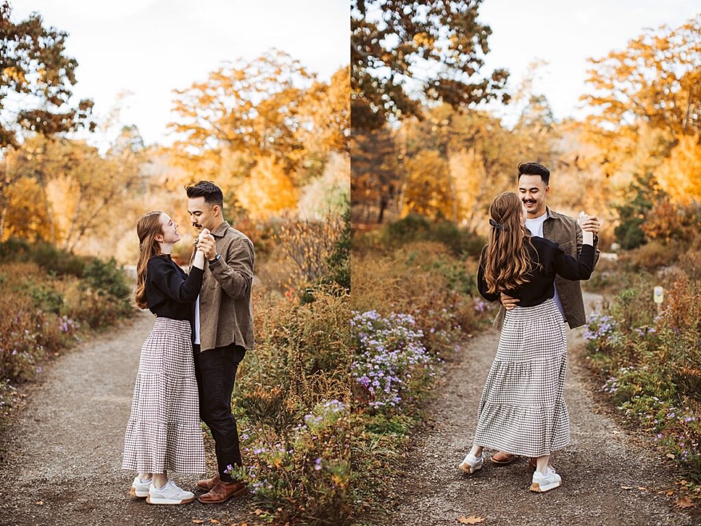 Couple slow dancing on a garden path surrounded by wildflowers and warm autumn foliage during engagement session.