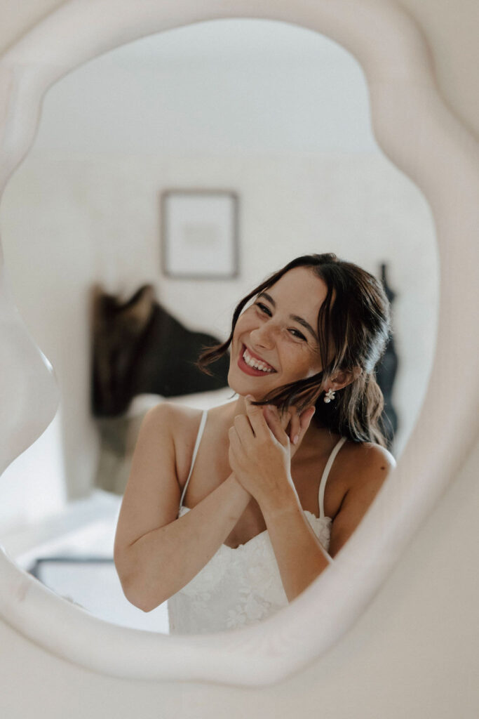Bride putting on earrings while looking in mirror, soft bridal portrait at Wentworth Inn