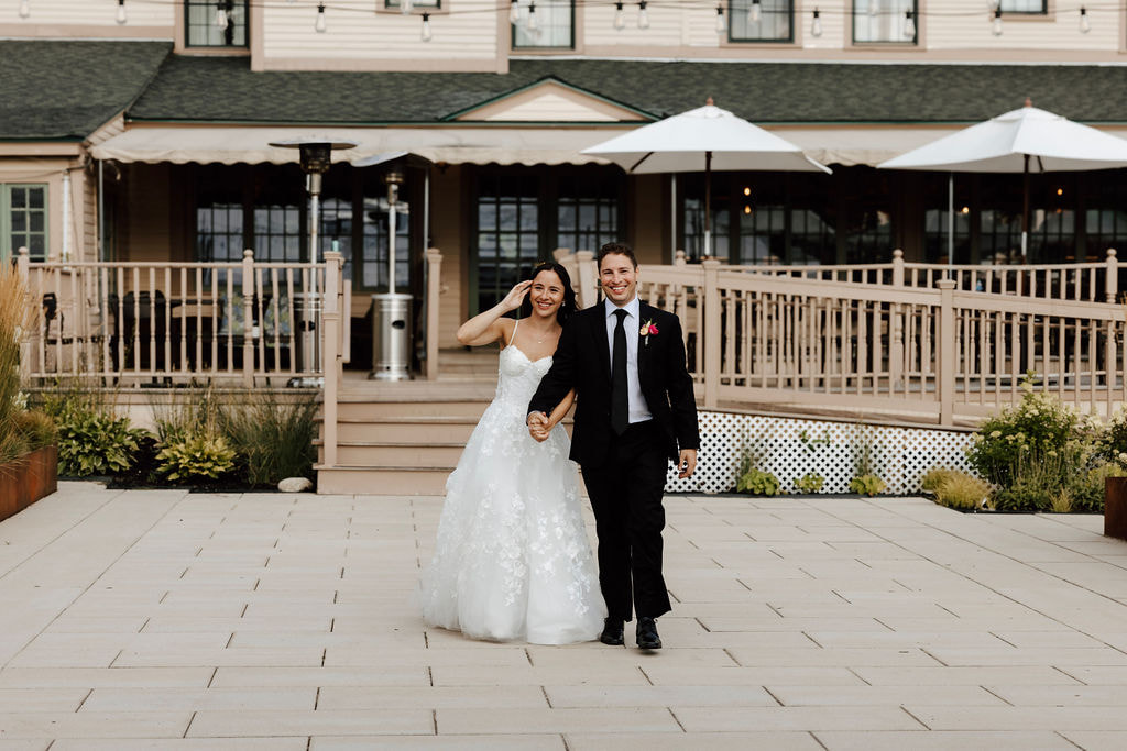 Bride and groom walking hand in hand outside Wentworth Inn reception space