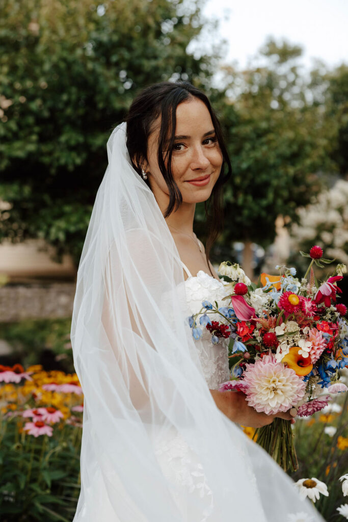 Close-up bridal portrait with veil and vibrant bouquet in garden setting