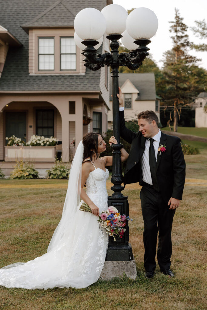 Bride and groom pose by street lamp, bride holding colorful bouquet, outdoor wedding portrait