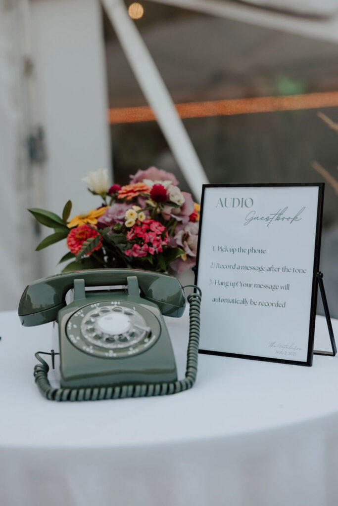 Vintage green rotary phone with audio guest book sign and flowers on table at wedding reception